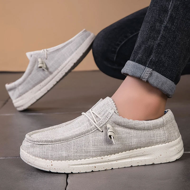 Lichtgrijze ademende mesh instaploafers met witte zool en veters, gedragen met een donkere jeans.