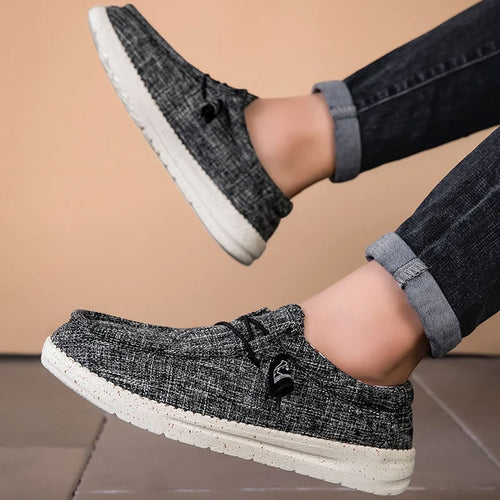 Donkergrijze ademende casual instap loafers met witte antislip zool, gedragen door een persoon.