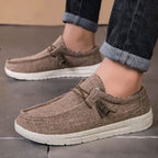 Bruine ademende casual instap loafers met witte zool en gespikkelde textuur, gedragen door een persoon.