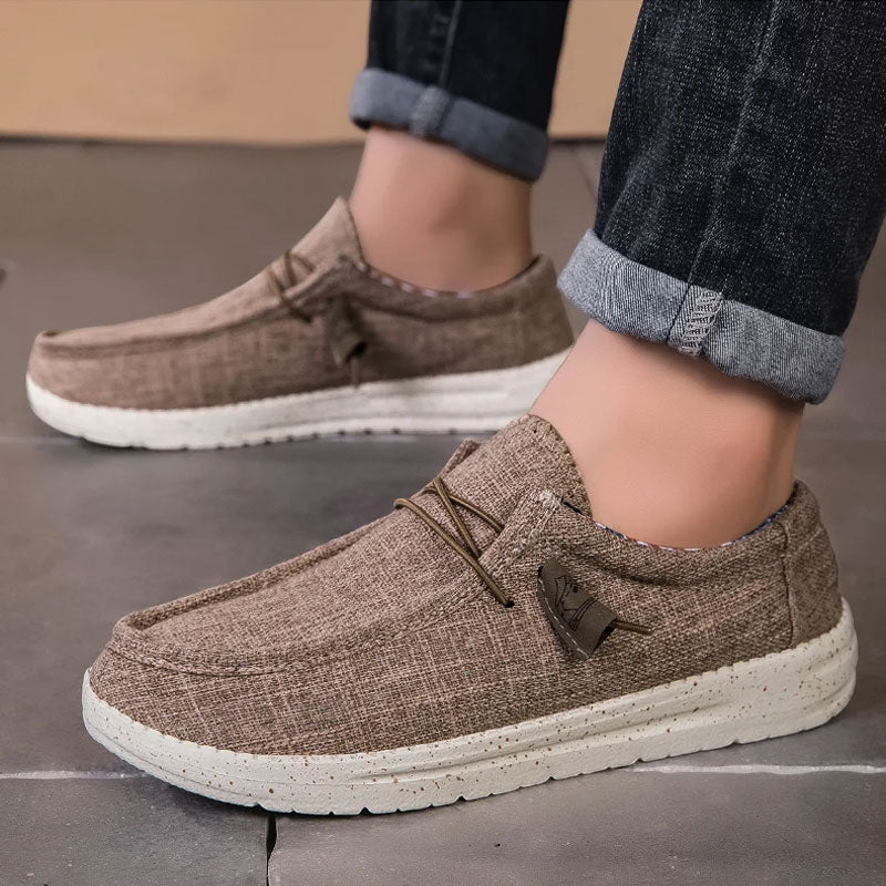 Bruine ademende casual instap loafers met witte zool en gespikkelde textuur, gedragen door een persoon.
