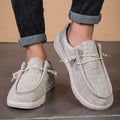 Lichtgrijze ademende mesh instaploafers met witte veters en zolen, gedragen door een persoon.