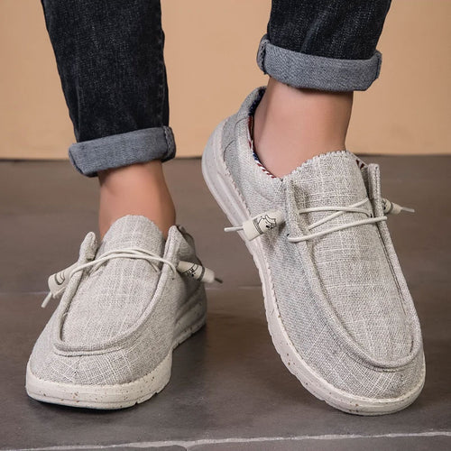 Lichtgrijze ademende mesh instaploafers met witte veters en zolen, gedragen door een persoon.