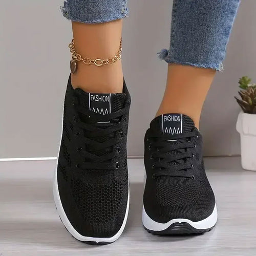 Zwarte ademende sneakers met mesh-bovenwerk, witte zool en veters.
