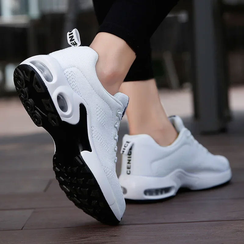 Witte ademende sneakers met mesh-bovenwerk, zwarte rubberen zool en luchtkussens.