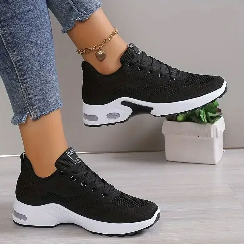 Zwarte ademende mesh sneakers met witte zool, veters en gouden enkelketting.