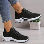 Zwarte ademende mesh sneakers met witte zool, veters en gouden enkelketting.