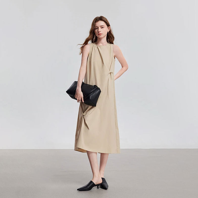 Model draagt een beige mouwloze midi jurk met ronde hals, getailleerde pasvorm en decoratieve knopen.