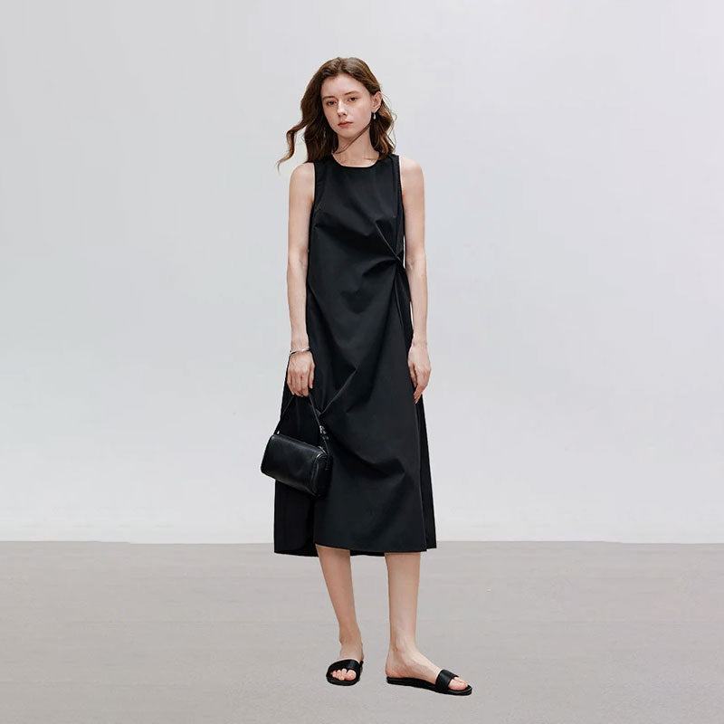 Vrouw draagt een minimalistische, mouwloze zwarte midi jurk met ronde hals en getailleerde pasvorm.