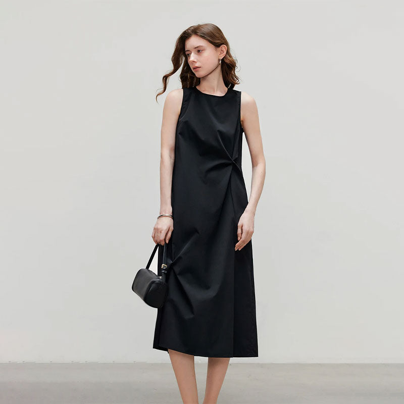 Model draagt een elegante zwarte mouwloze midi jurk met ronde hals en getailleerde pasvorm.