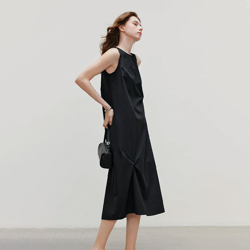 Model draagt een elegante zwarte mouwloze midi jurk met ronde hals en getailleerde pasvorm.