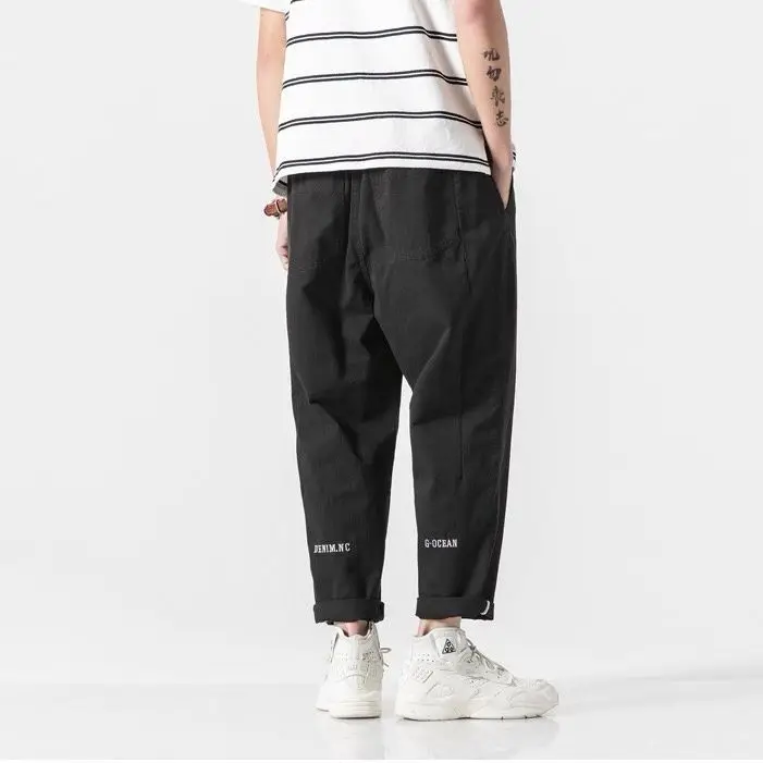 Zwarte katoenen wide leg cargo broek met elastische taille, opgerolde enkels en witte tekstprints.
