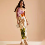 Elegante one shoulder maxi jurk met artistieke bloemenprint, golvende zoom en split, gecombineerd met hakken en tasje.