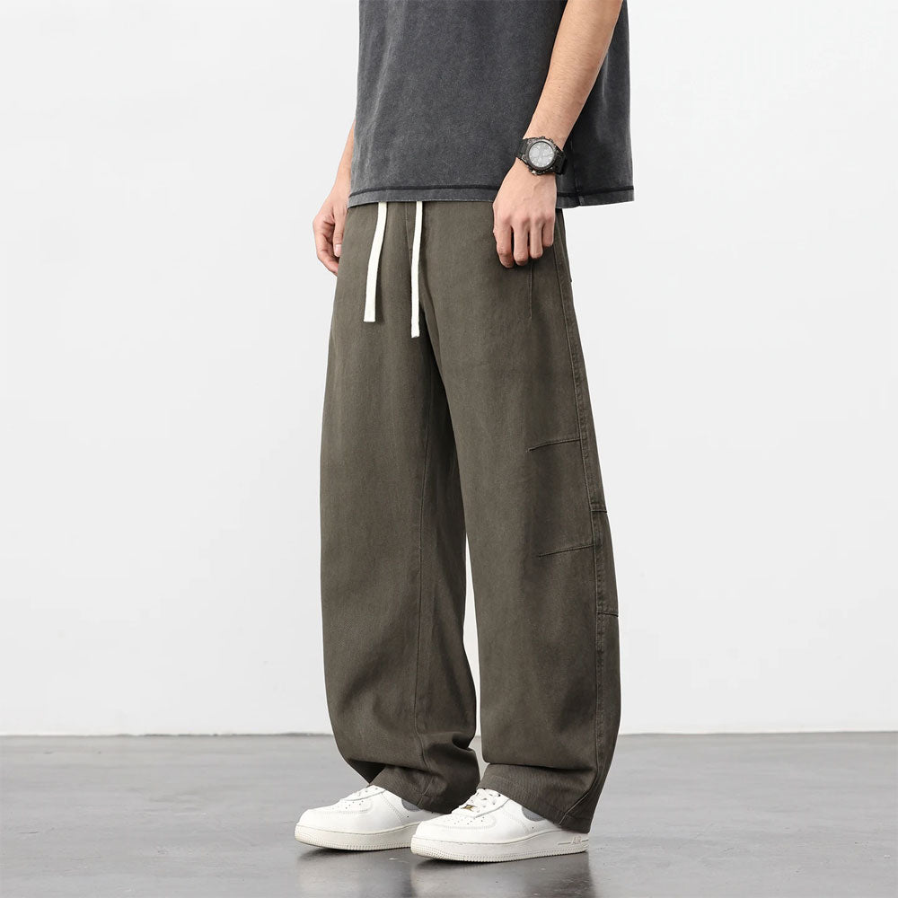 Donkergroene retro katoenen workwear broek met losse pasvorm, trekkoord en witte sneakers.