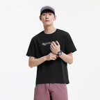 Man draagt een zwart sneldrogend sport T-shirt met witte print, grijze pet en roze shorts.