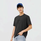 Man draagt zwart T-shirt met subtiele gradient letterprint, blauwe pet en jeans.