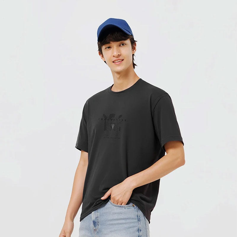 Man draagt zwart T-shirt met subtiele gradient letterprint, blauwe pet en jeans.